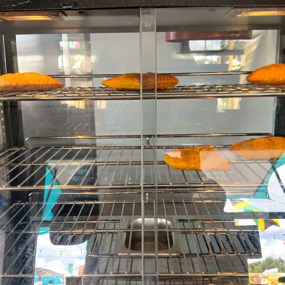 A glass display case holds several golden-brown baked pastries on wire racks.